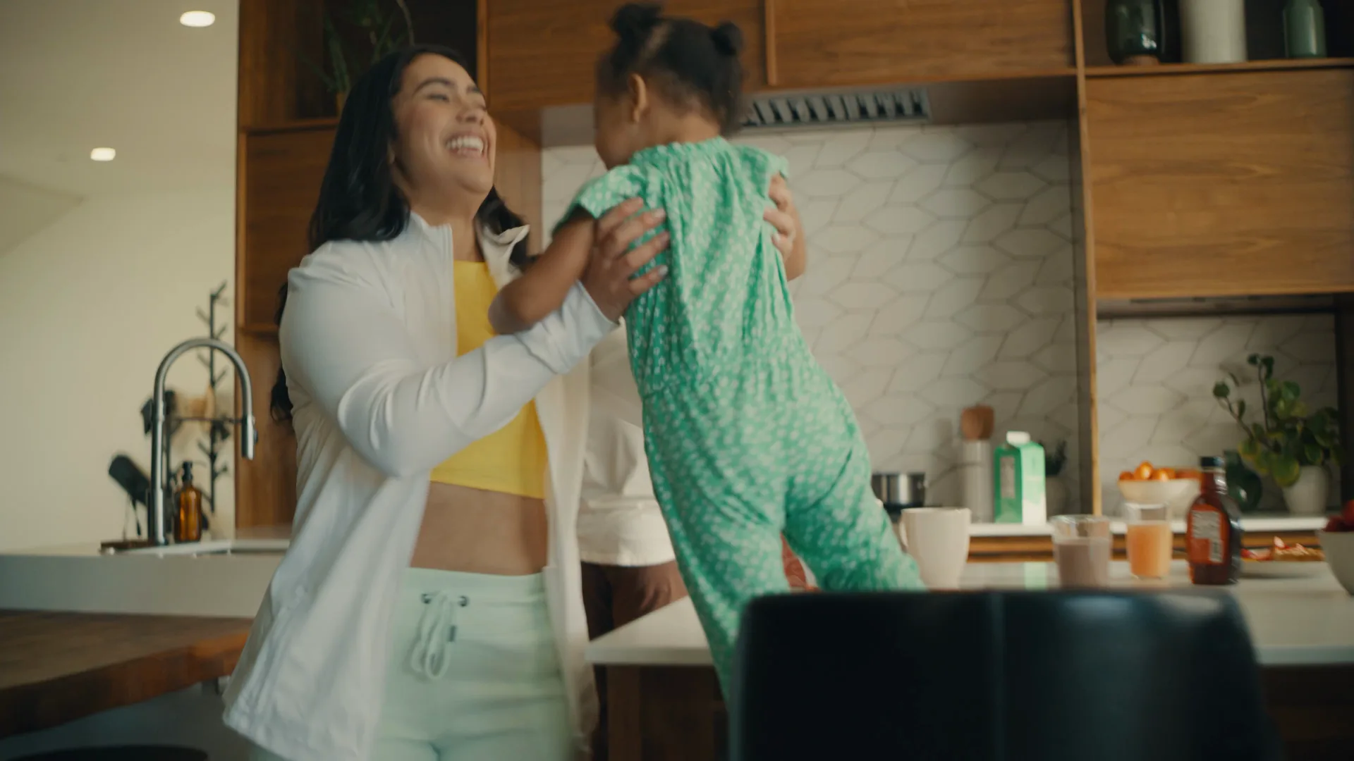 Mother lifting her daughter in a kitchen