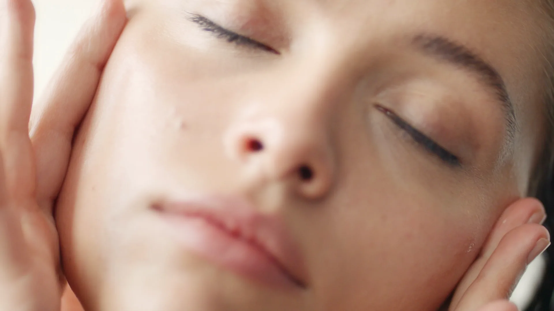 Close-up of hands on cheeks, eyes closed