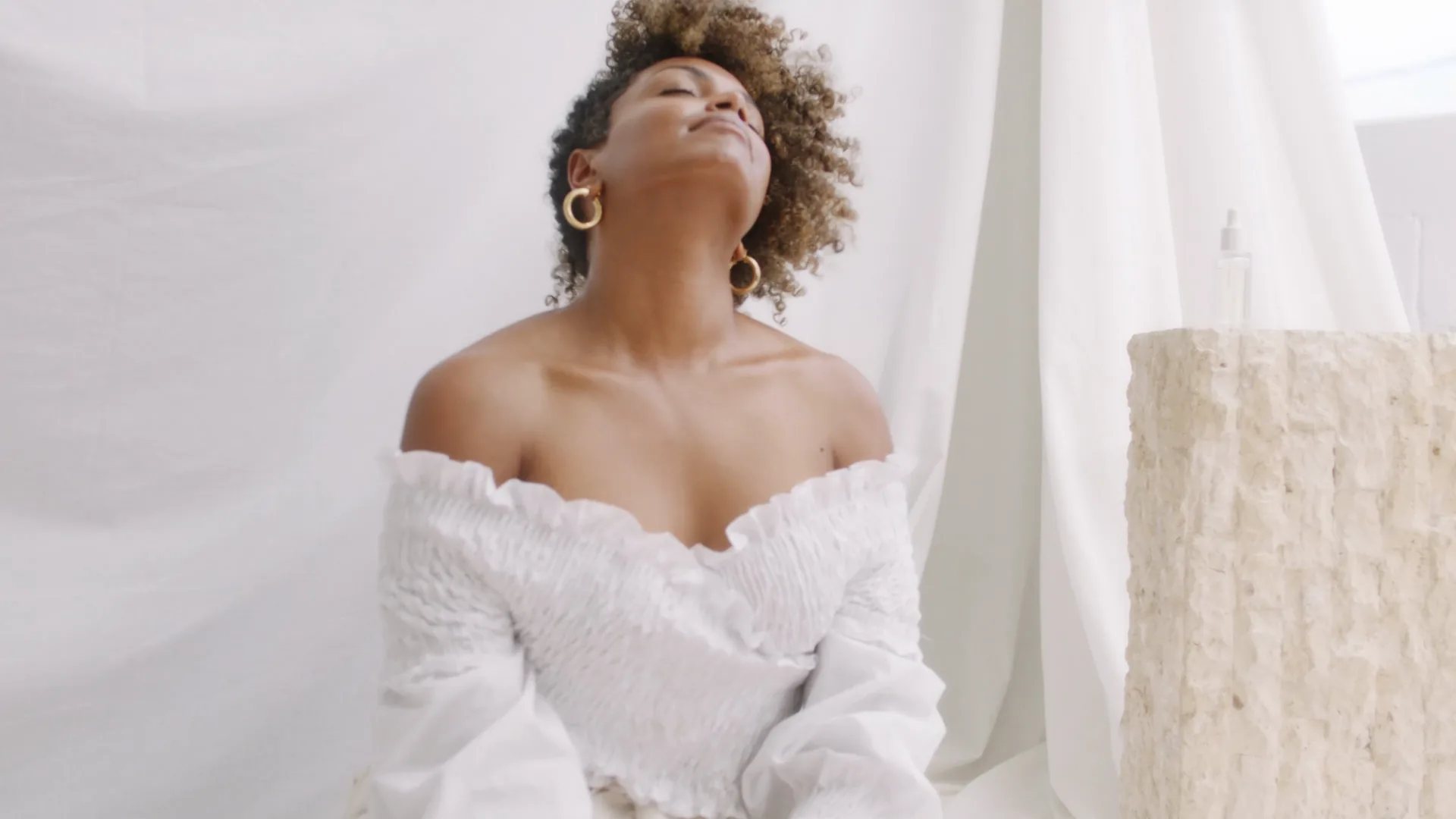 Woman in a white off-shoulder top, head tilted back