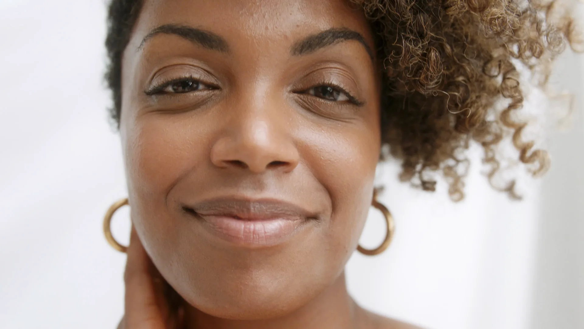 Close portrait, hand at her neck, smiling