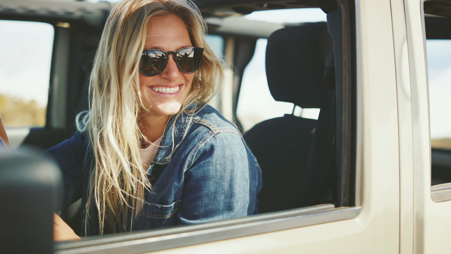 A smiling driver in sunglasses at a car window