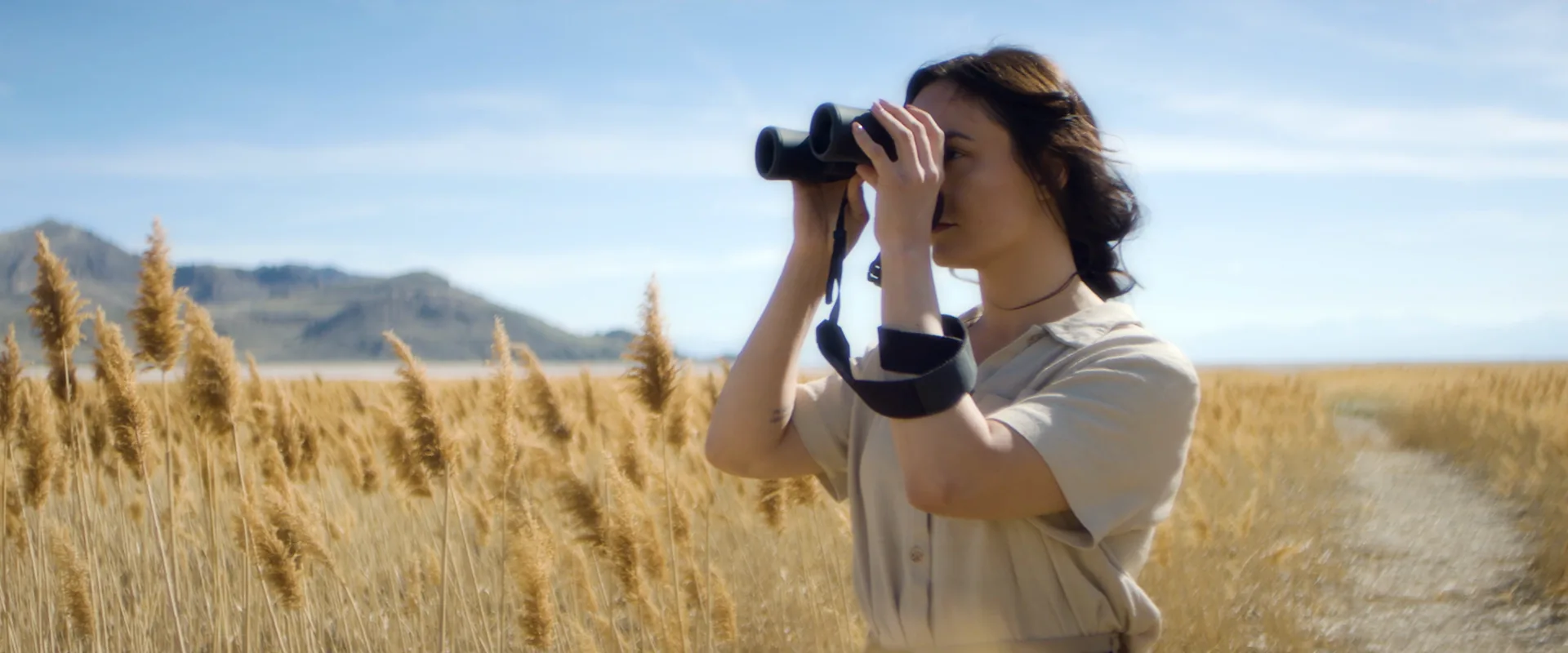 Woman with binoculars in a field of tall grass