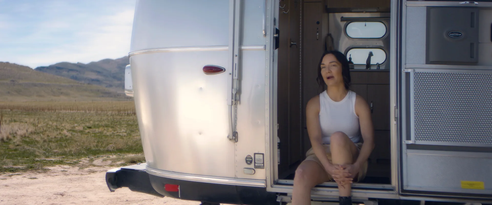 Woman sitting in the doorway of a vintage trailer