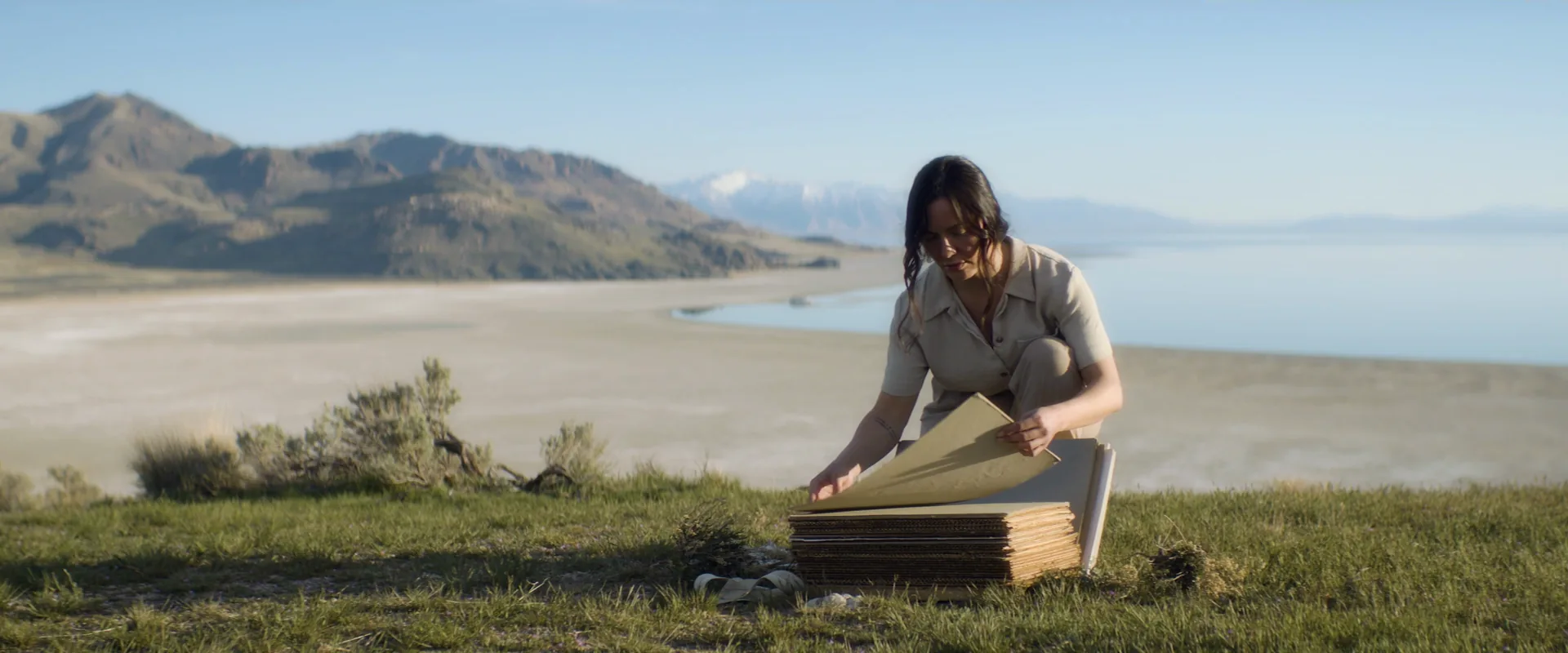 Woman kneeling on a shoreline with a field press