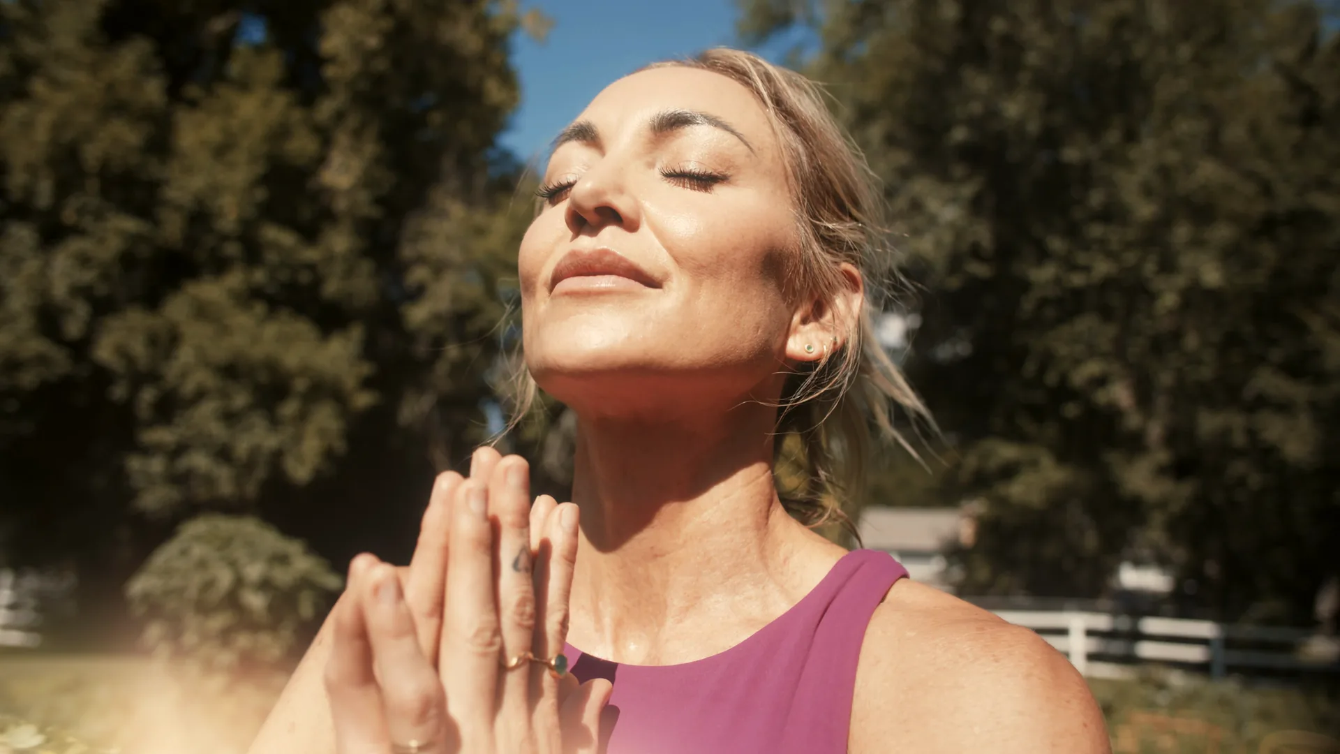 Woman with eyes closed, face to the sun in a garden